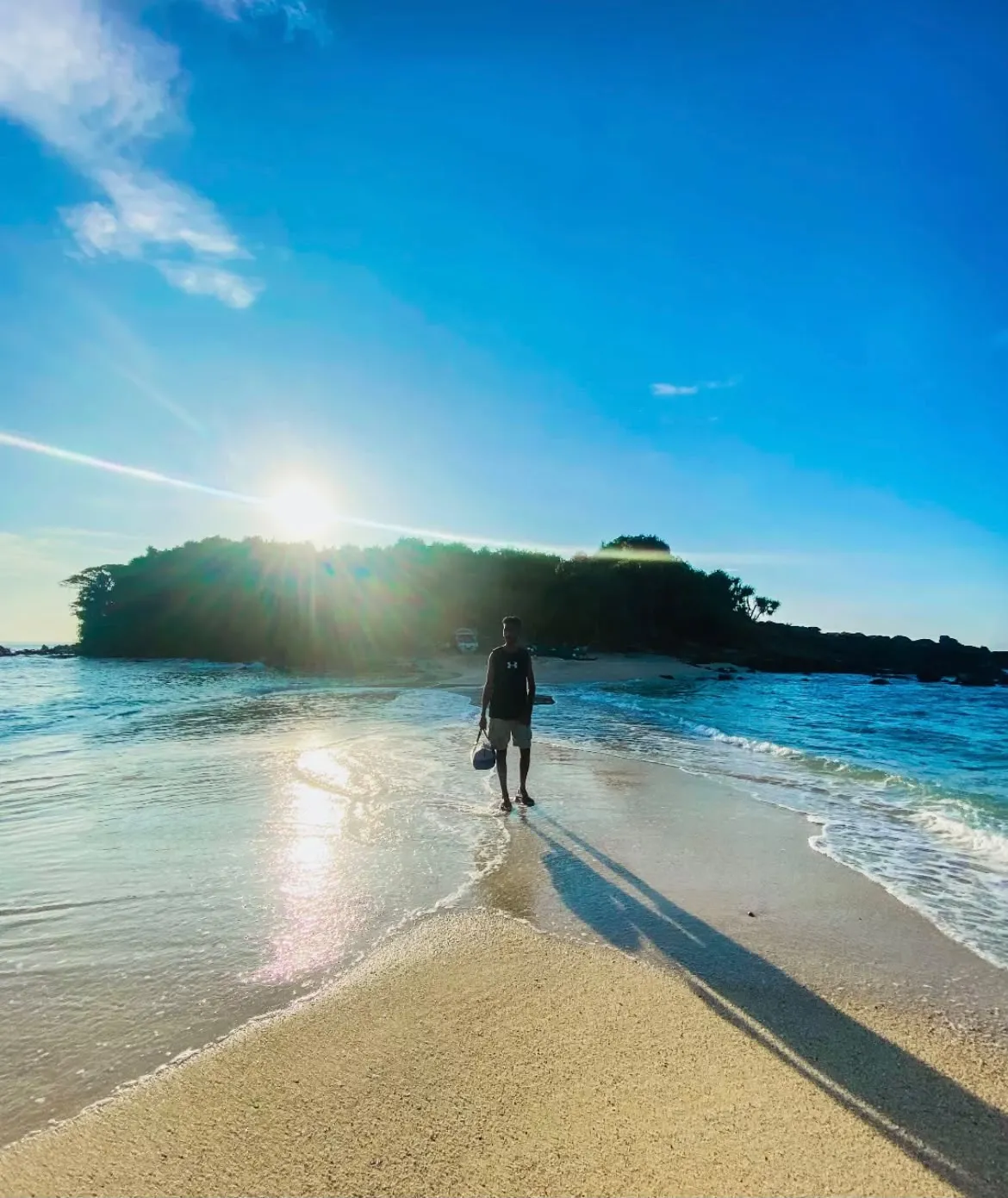 A visitor walking out on the sandbar towards Blue Beach Island in the morning sun