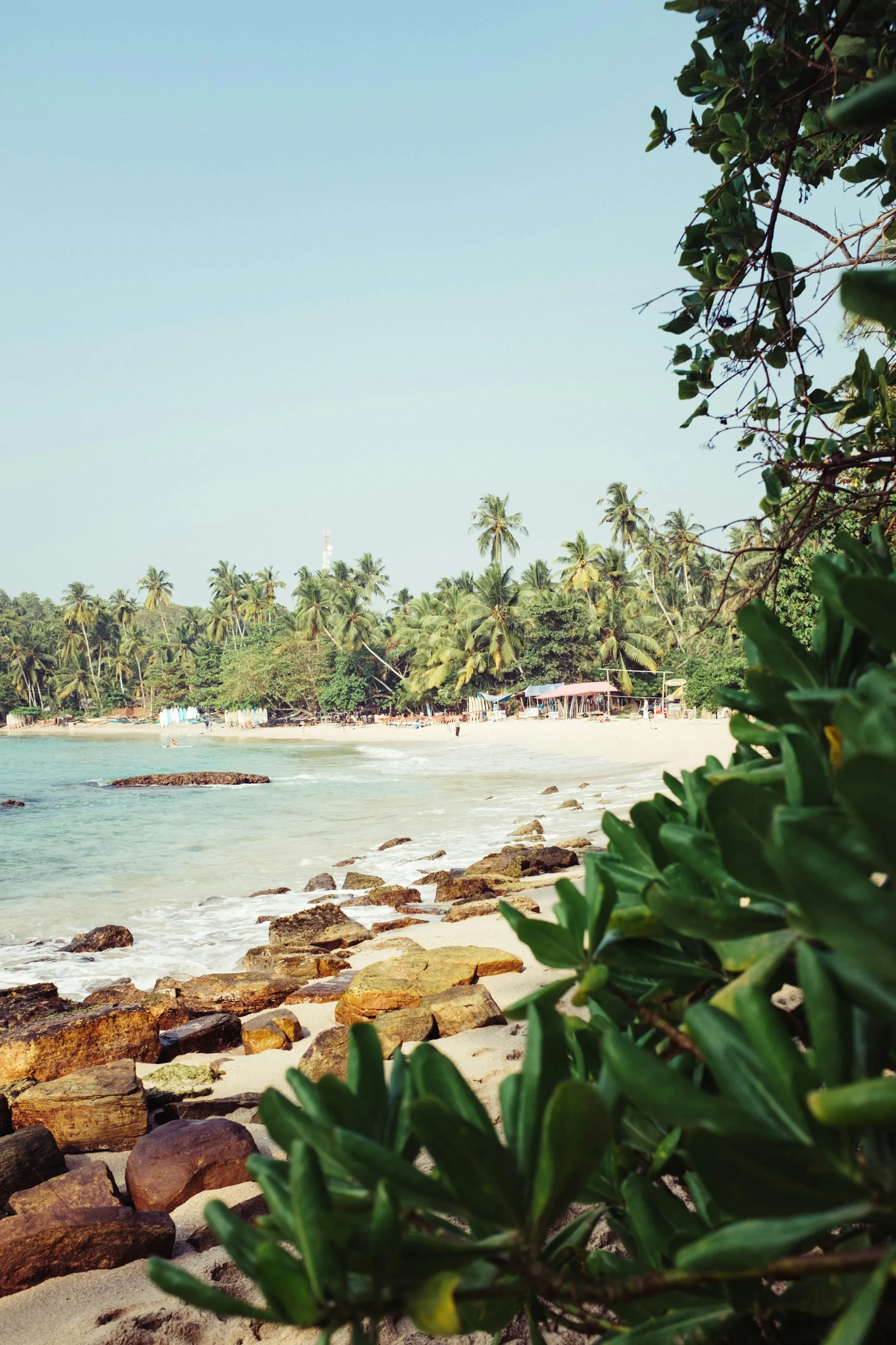 The beach at Hiriketiya Bay, framed by rocks and palm trees