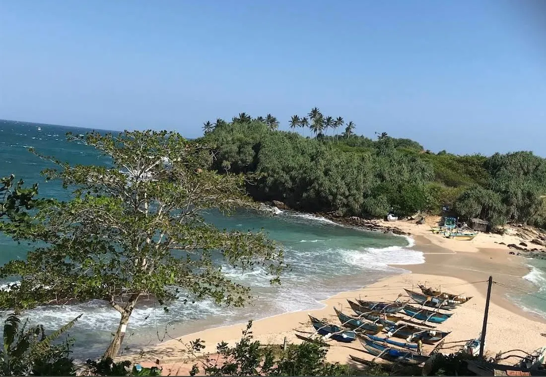 Fishing boats pulled up on Nilwella Beach, with palms and green hills behind